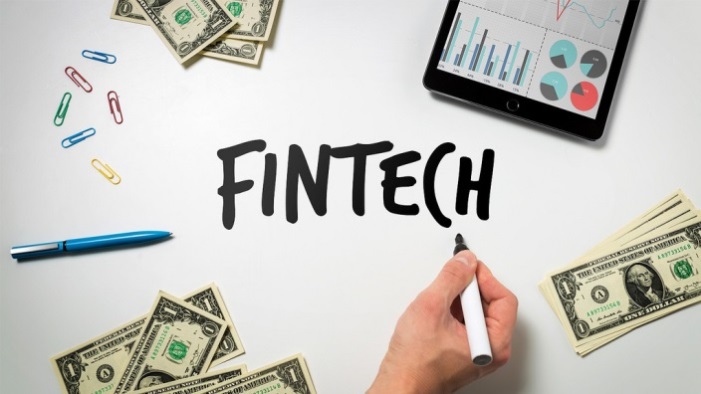 The word FinTech written in marker with money on the table.