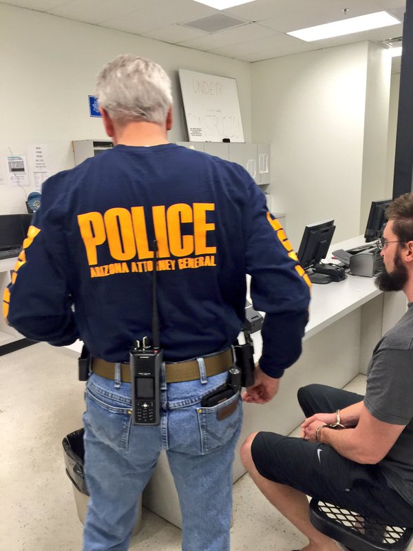 Special Agent arresting suspect who is sitting at the computer