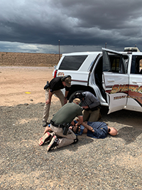 Men arresting a crash dummy during a training exercise.