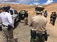 Law enforcement standing, talking next to a vehicle during a training exercise.